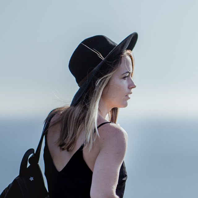 Woman walks with a hat and a backpack